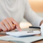 Frau rechnet am Taschenrechner Bewirtschaftungskosten aus